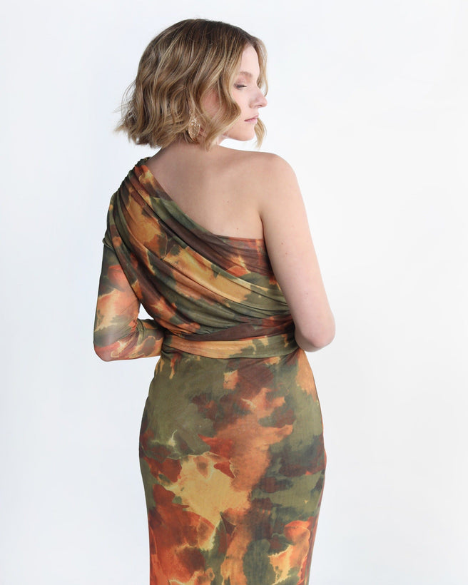 Auka Studio KENIA DRESS vestido with a flowing design, displayed on a hanger against a neutral background.